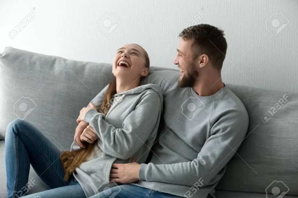 94055648 young happy couple having fun talking laughing relaxing at home on couch boyfriend embracing girlfri