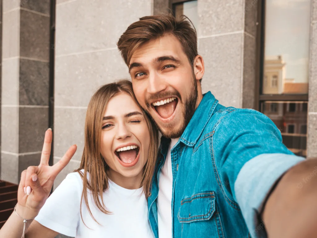 smiling beautiful girl her handsome boyfriend casual summer clothes happy family taking selfie self portrait themselves smartphone camera shows peace sign winking street 158538 5459